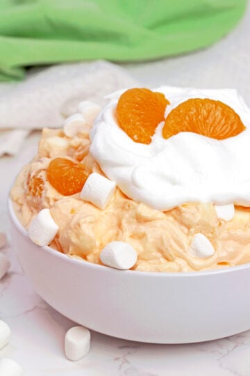 Creamsicle Orange Cheesecake Fluff Salad served in a bowl with mandarin oranges and mini marshmallows.