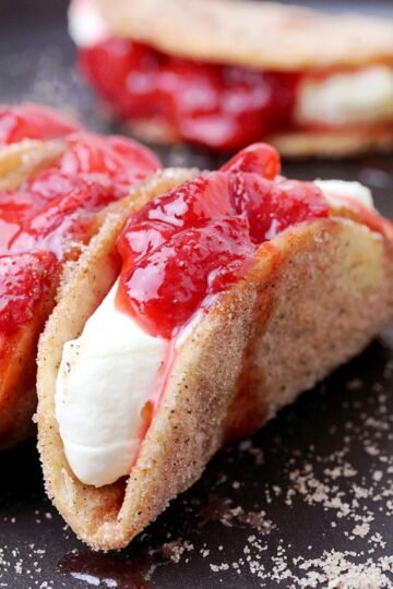 Strawberry Cheesecake Tacos - crunchy cinnamon and sugar tortilla shells, filled with cheesecake and topped with homemade strawberry sauce are perfect bites for every occasion. They are so easy to make, they look great and taste even better.