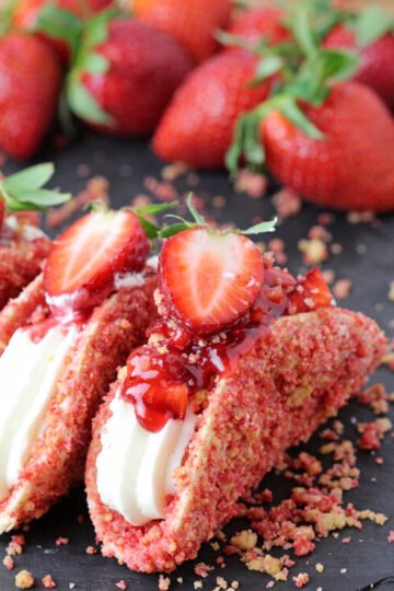 Strawberry Crunch Cheesecake Tacos - crunchy tortilla shell coated in white chocolate and strawberry crunch, creamy cheesecake filling, topped with fresh strawberries and strawberry syrup is a true delight!