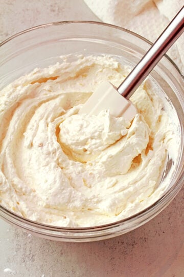 Coconut pineapple cream cheese frosting in a bowl, light and fluffy texture.